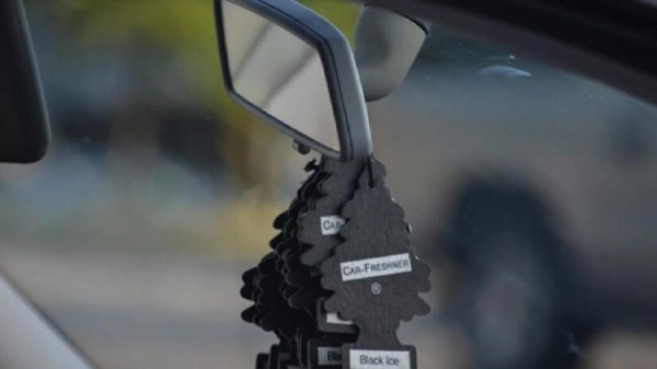 A rearview mirror with several air fresheners hanging from it