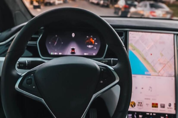 A driver's perspective of the steering wheel, dash and windshield while driving down the road.