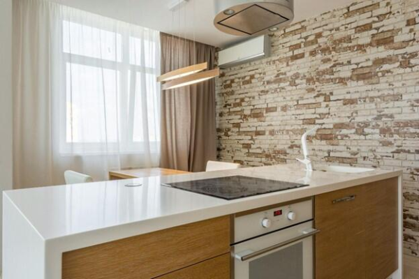 A modern kitchen featuring a white countertop and a rustic brick wall, creating a stylish and inviting atmosphere.