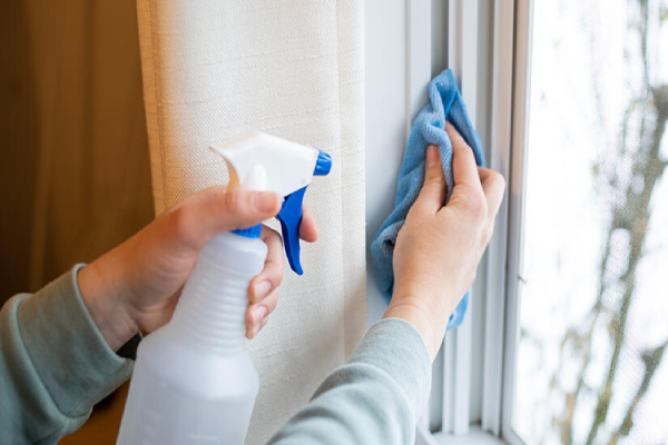 A person using a window cleaner to wipe a glass window, ensuring it is clean and streak-free.
