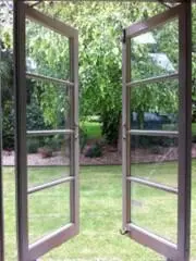 a brown casement opened outward towards a grassy backyard