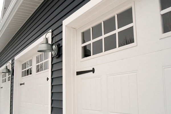 Garage doors with windows and side lights, enhancing the exterior of a house.
