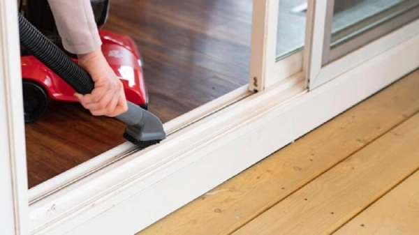 A sliding glass door track being vacuumed