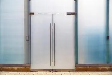 a swinging glass storefront door with two door handles attached to it