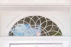 a white floral designed window above a door