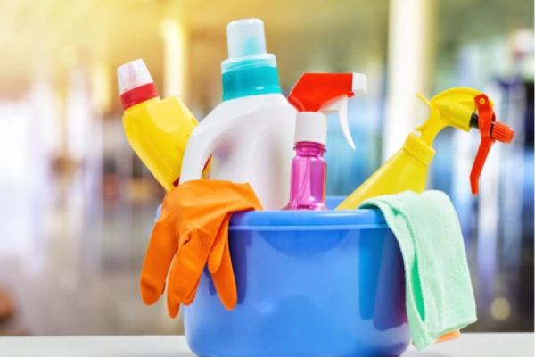 A bucket filled with various cleaning supplies placed on a table.